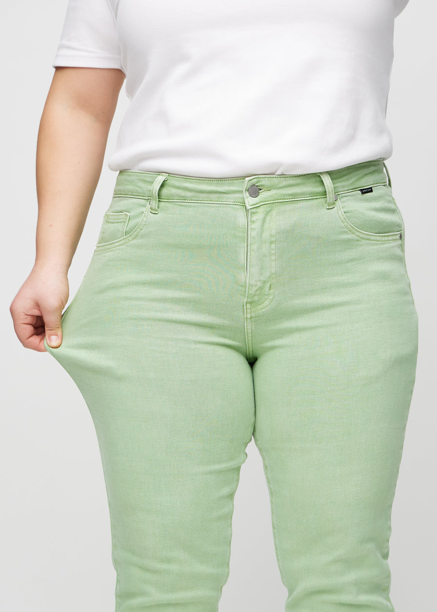 The plus-size model stretches the jeans at the thigh to show the stretch.
