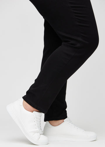 Slim jeans for women in black, color Ravens. Close-up at the ankles on a plus-size model, showing the fit at the leg openings.