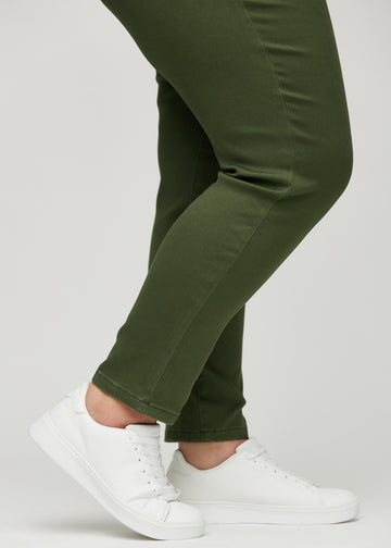 Slim jeans for women in dark green, color Renewals. Close-up at the ankles on a plus-size model, showing the fit at the leg openings.