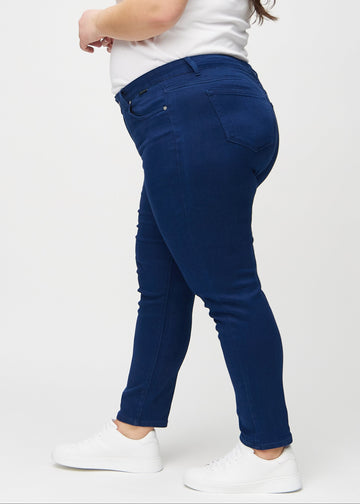 Dark blue slim jeans seen from the side on a plus-size model.