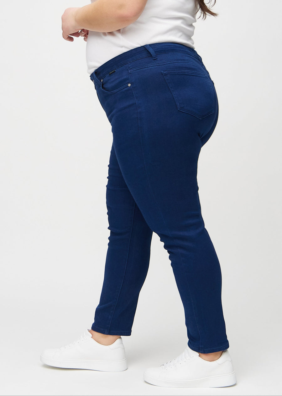 Dark blue slim jeans seen from the side on a plus-size model.