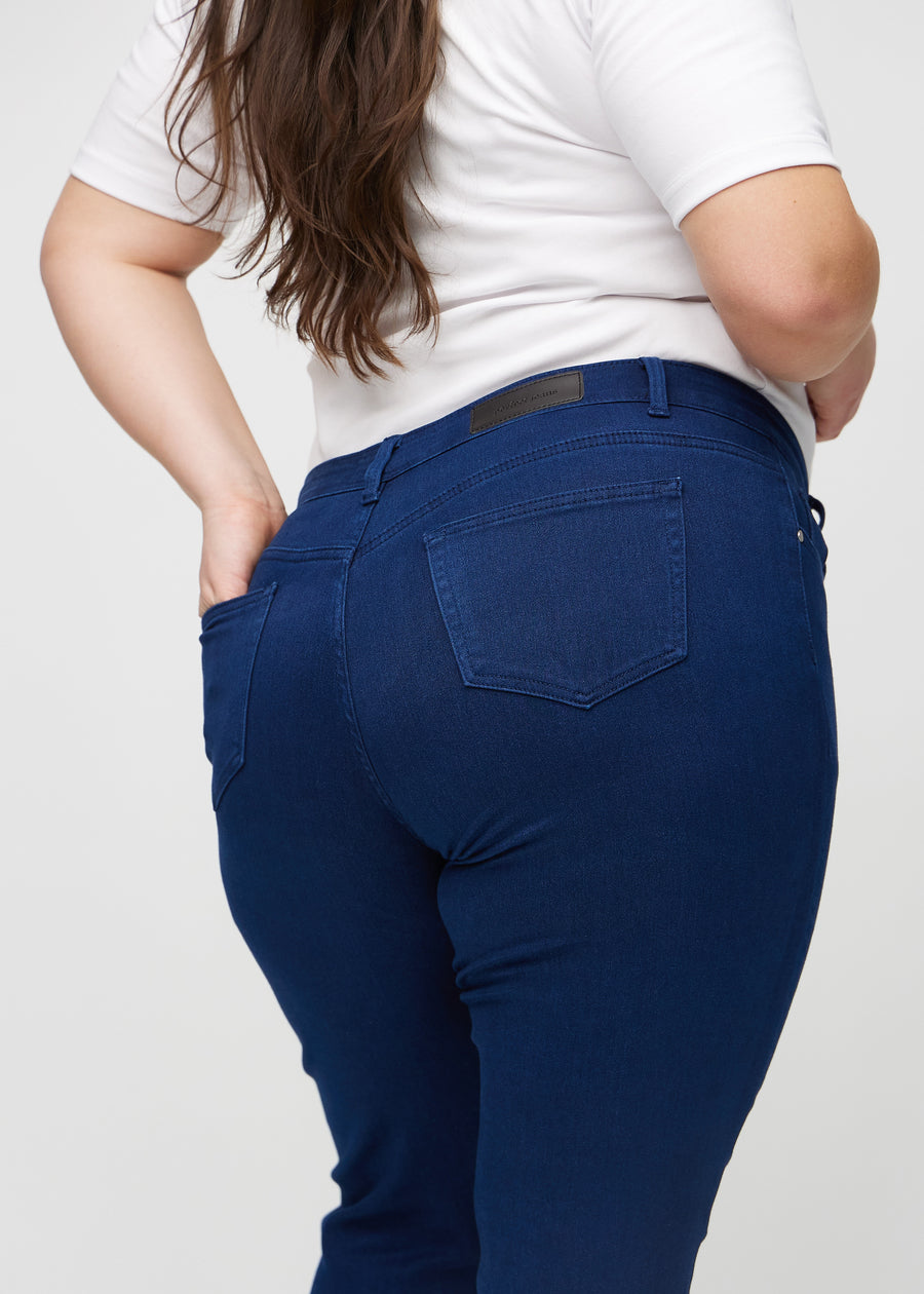 Dark blue slim jeans seen from the back close up on a plus-size model to show details.