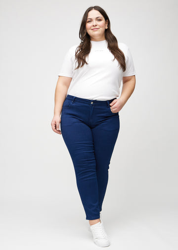 Full image of a plus-size model in dark blue slim jeans.