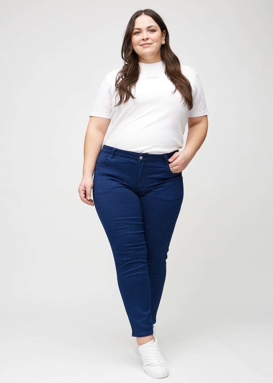 Full image of a plus-size model in dark blue slim jeans.