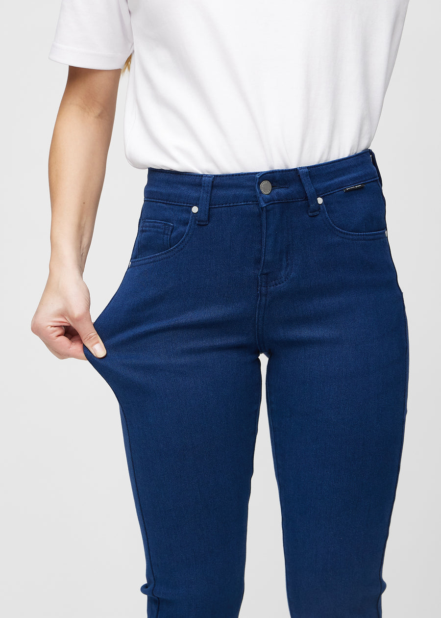 The model stretches the jeans at the thigh to show the stretch.