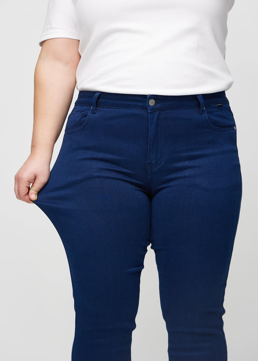 The plus-size model stretches the jeans at the thigh to show the stretch.