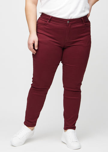 Slim jeans for women in dark red, color Santas. Front view on a plus-size model, showing a close fit through the leg with a little more room at the ankle.