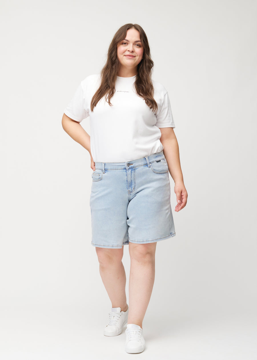 Full-length view of a female model wearing light blue Waves denim shorts with a mid-rise waist and loose fit.