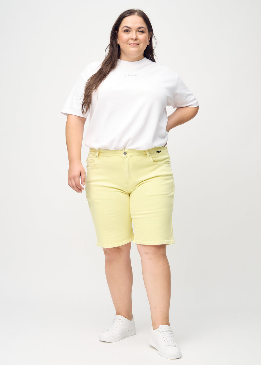 Full image of a plus-size model in light yellow regular middle shorts.