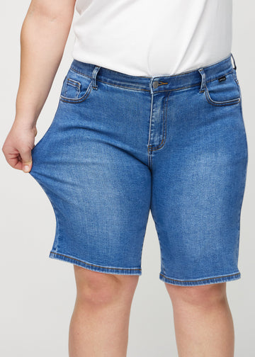 The plus-size model stretches the shorts at the thigh to show the stretch.