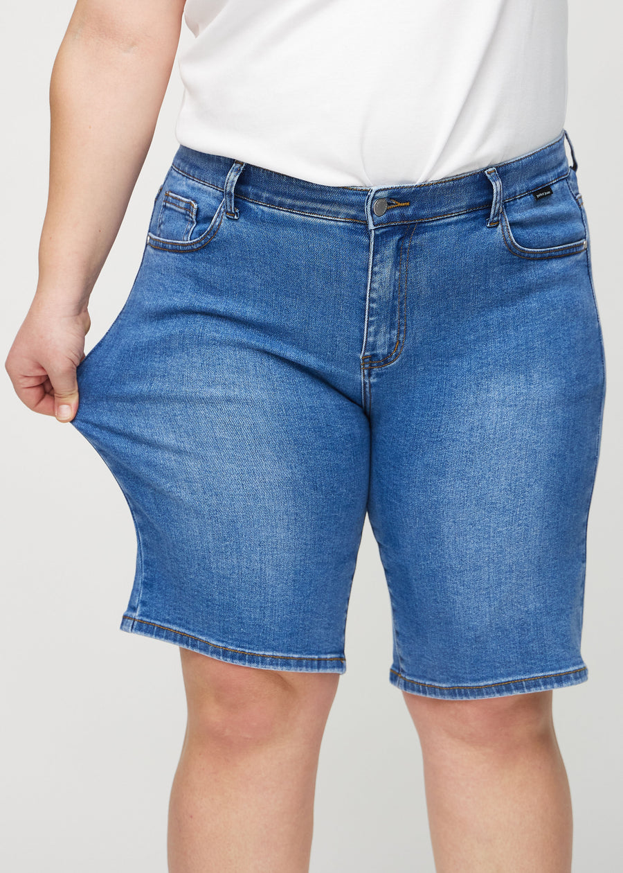 The plus-size model stretches the shorts at the thigh to show the stretch.