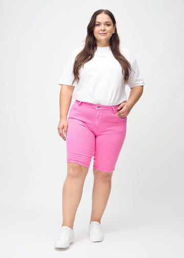 Full image of a plus-size model wearing light pink skinny middle shorts.