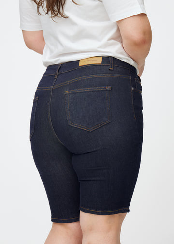 Deep dark blue denim shorts for women in the colour Midnights seen from the back in close-up on a plus-size model.