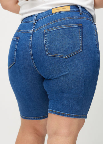 Dark denim skinny middle shorts seen from the back close up on a plus-size model to show details.