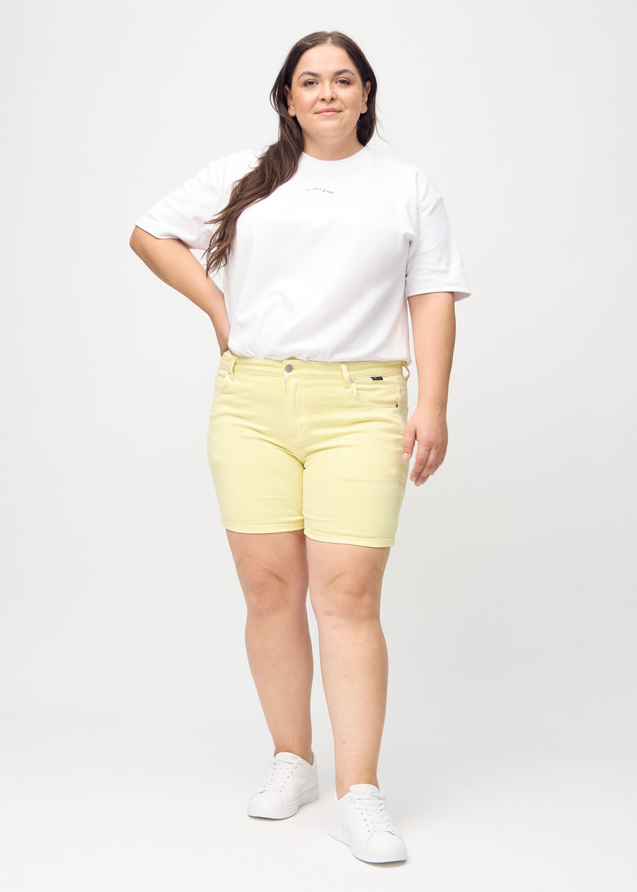 Full image of a plus-size model wearing light yellow skinny short shorts.