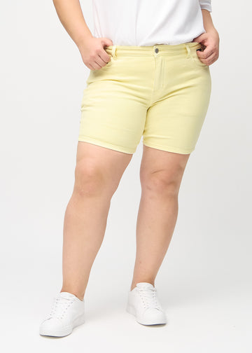 Light yellow skinny short shorts, model name Lemonades, which fit tightly and end mid-thigh on a plus-size model, seen from the front.