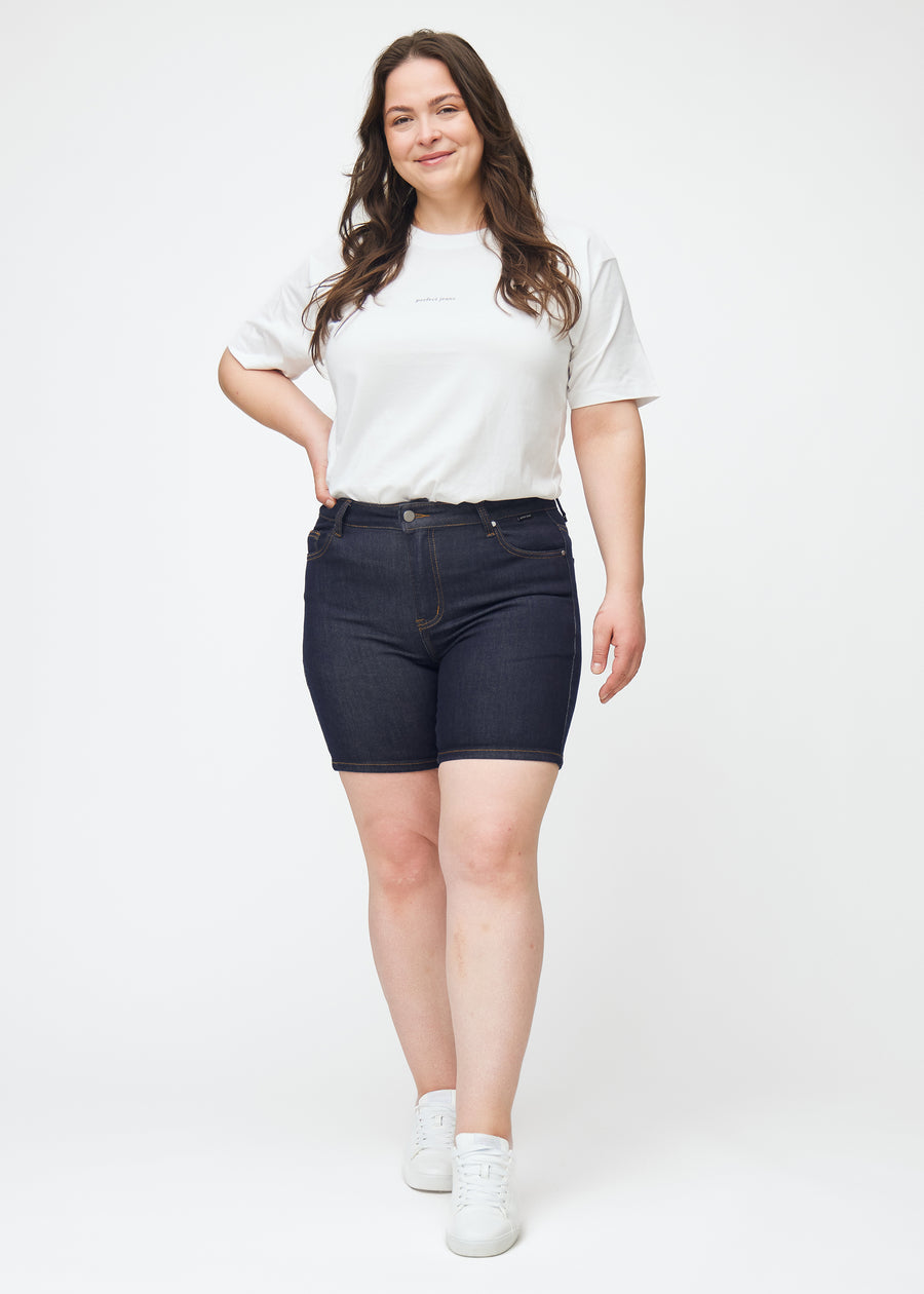 Full image of a plus-size model wearing deep dark blue denim shorts for women in the colour Midnights with a skinny fit.