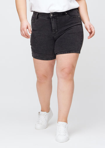 Dark grey denim skinny short shorts, model name Shadows, which are tight-fitting and end mid-thigh on a plus-size model, seen from the front.