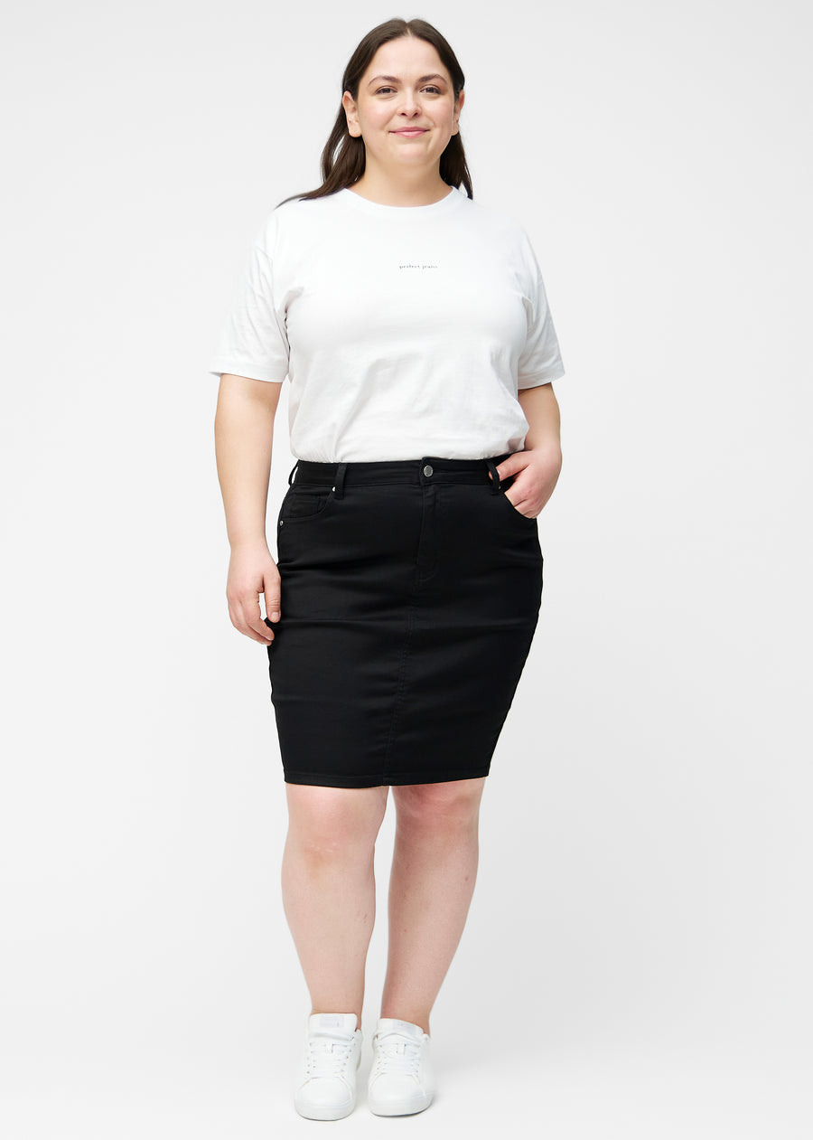 Fuldt billede af plus-size model i sort, tætsiddende og knælang jeansnederdel.