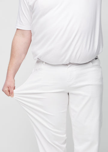 The plus-size model stretches the jeans at the thigh to show the stretch.