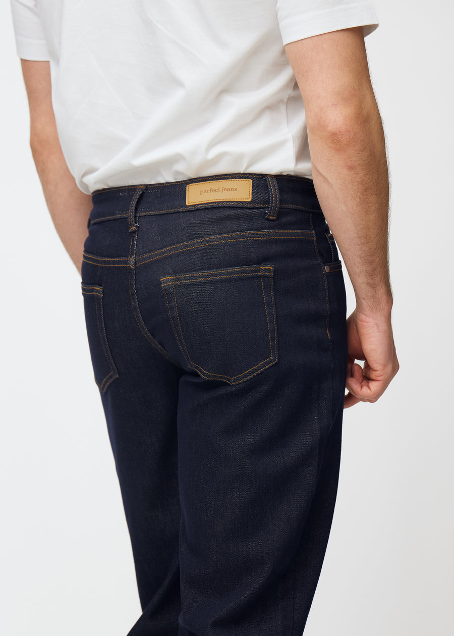 Deep dark blue denim jeans for men in the color Midnights seen from the back in close-up to show fit and details.