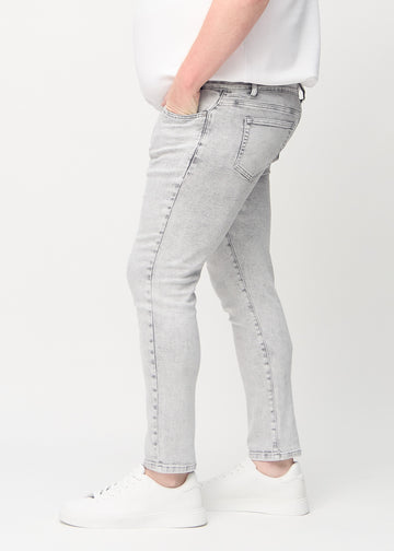 Light grey denim slim jeans viewed from the side on a plus-size model.