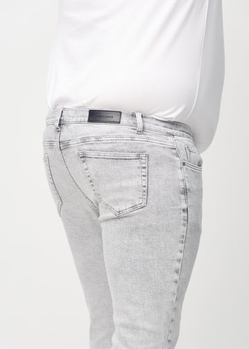 Close-up back view of light grey denim slim jeans on a plus-size model showing details.