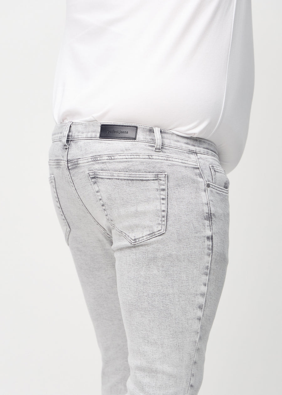 Close-up back view of light grey denim slim jeans on a plus-size model showing details.