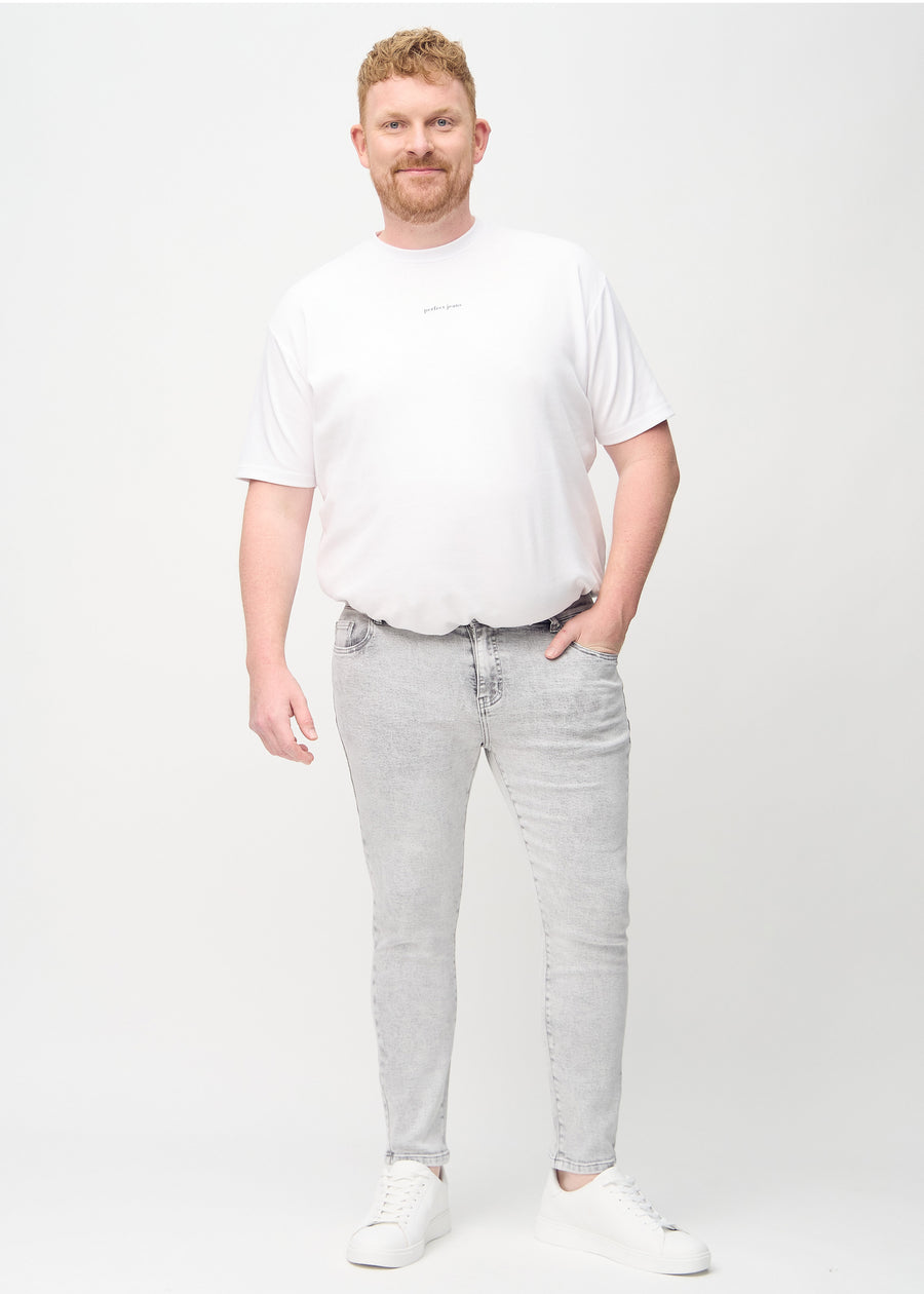 Full-length view of a plus-size model in light grey denim slim jeans.