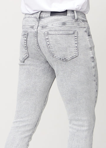 Close-up back view of light grey denim slim jeans showing details.