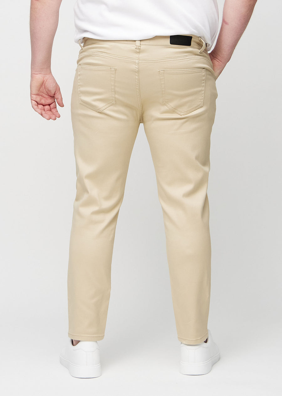 Beige slim jeans set bagfra på en plus-size model, så man kan se hele produktet.