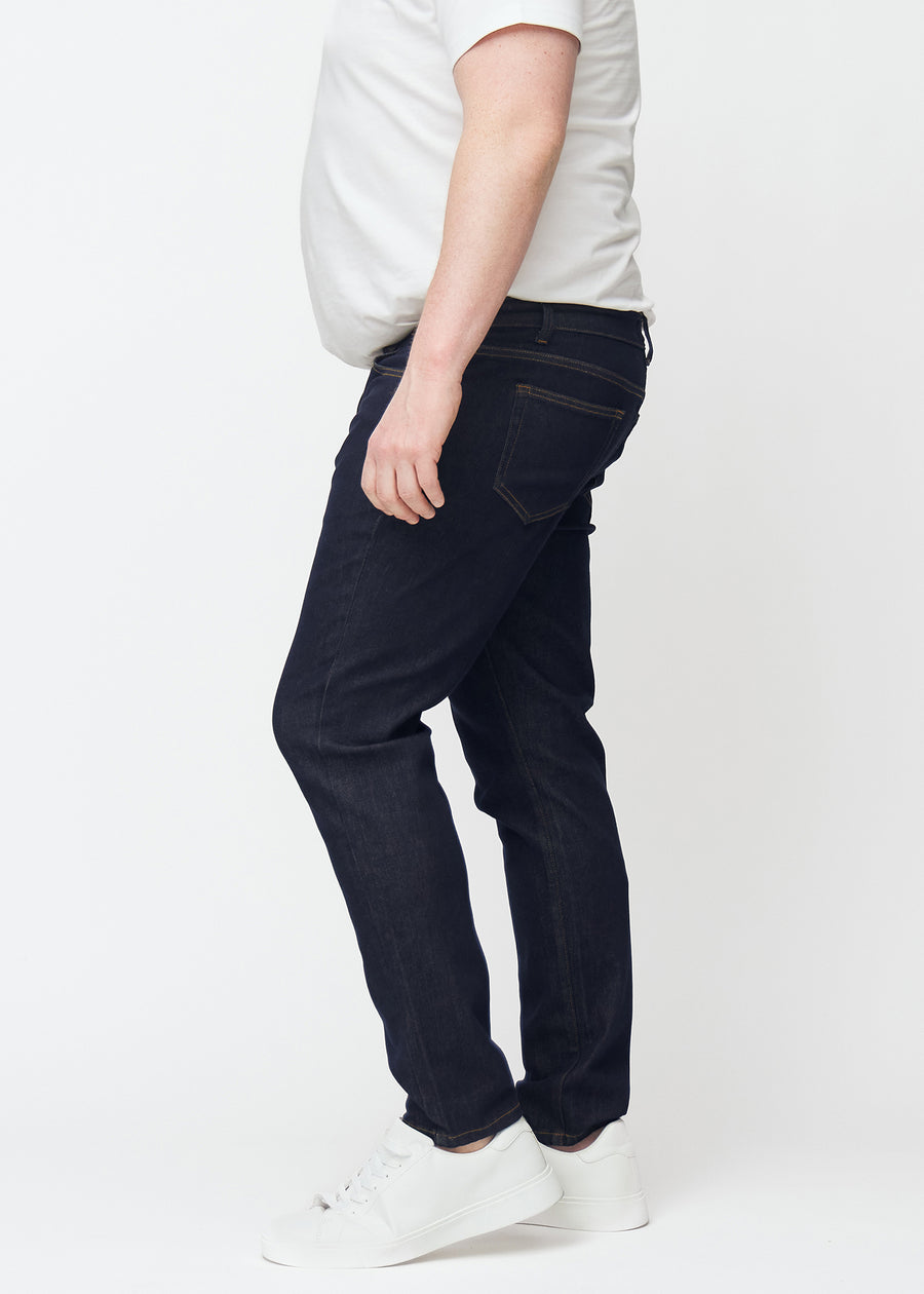 Deep dark blue denim jeans for men in the color Midnights with a slim fit seen from the side on a plus-size model.