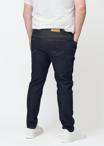 Deep dark blue denim jeans for men in the color Midnights seen from the back on a plus-size model.