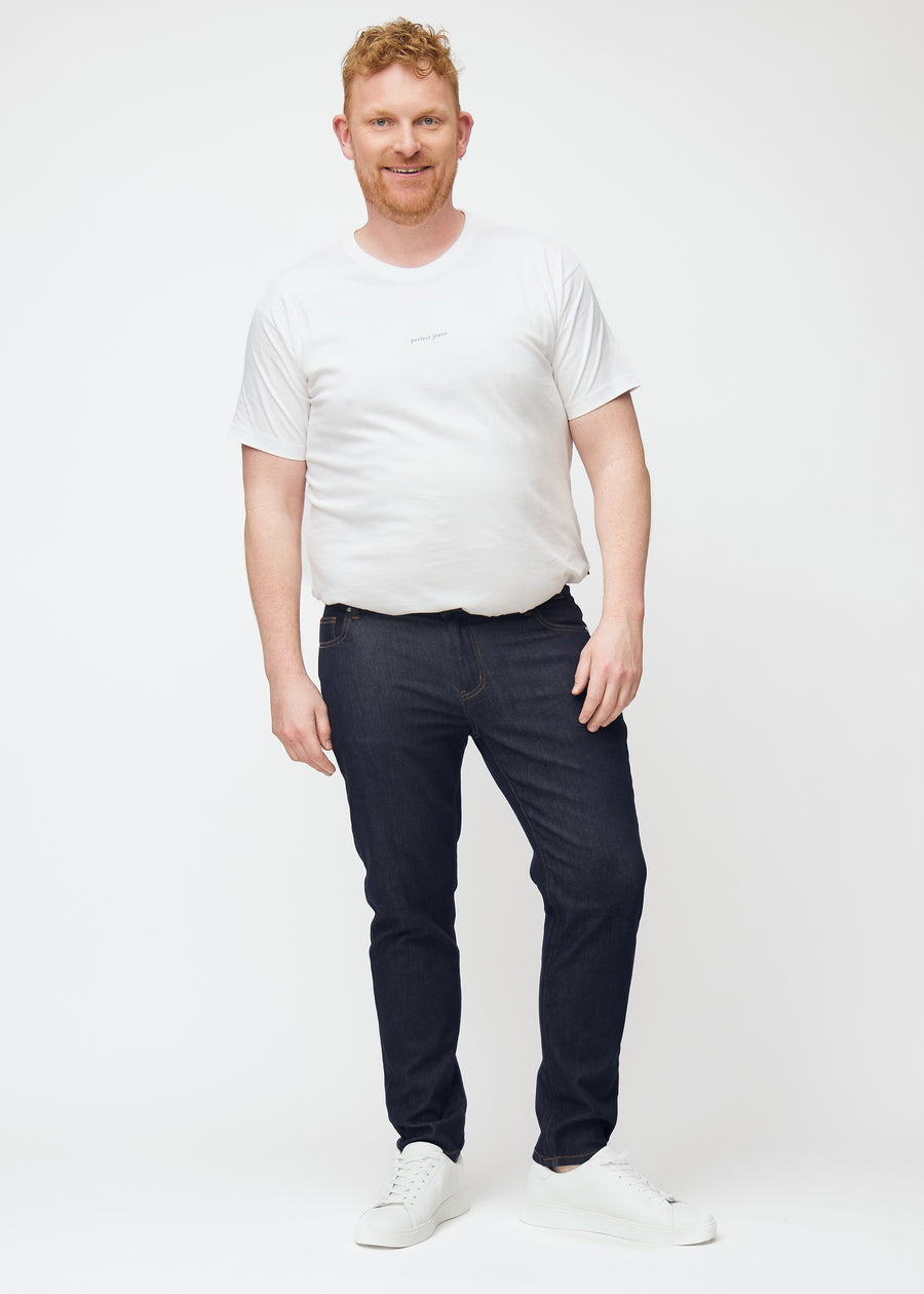 Full image of plus-size model in deep dark blue denim jeans for men in the color Midnights with a slim fit.