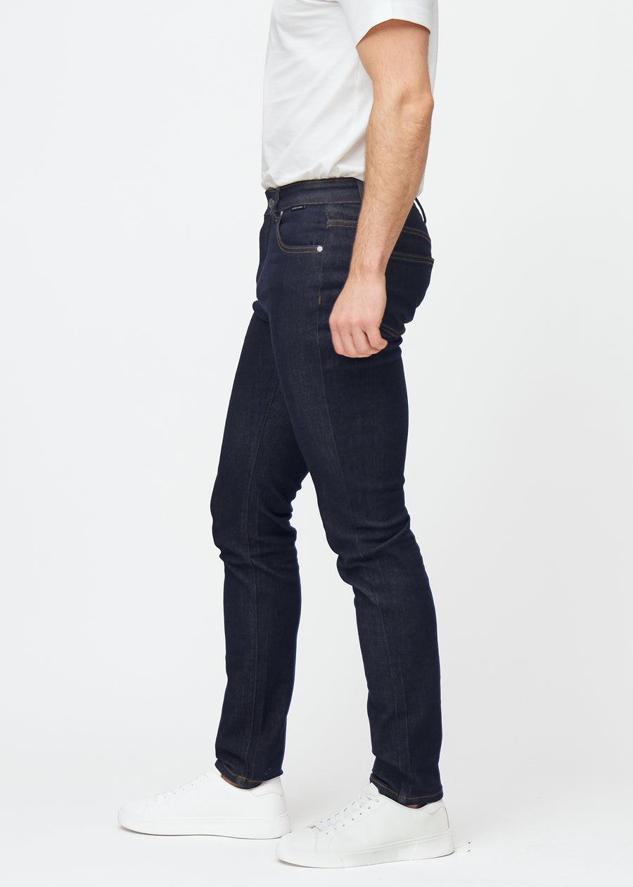 Deep dark blue denim jeans for men in the color Midnights with a slim fit seen from the side on a model.