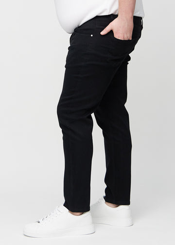 Black slim jeans viewed from the side on a plus-size model.