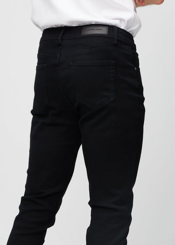 Close-up back view of black slim jeans showing details.