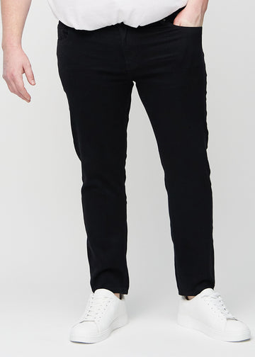 Black slim jeans, model name Ravens, fitted closely along the legs on a plus-size model, front view.