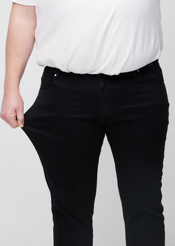 Plus-size model stretches the jeans at the thigh to show the fabric&