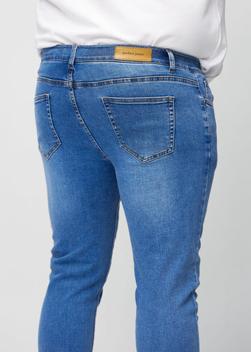 Close-up back view of blue denim slim jeans on a plus-size model showing details.