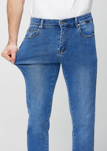 Model stretches the jeans at the thigh to show the fabric&