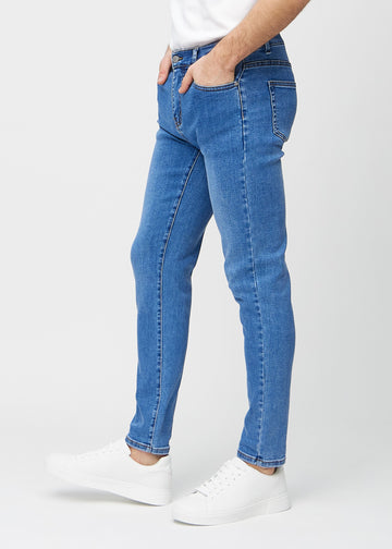Blue denim slim jeans viewed from the side on a model.