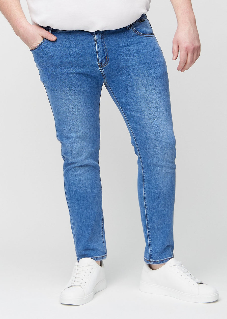 Blue denim slim jeans, model name Rivers, fitted closely along the legs on a plus-size model, front view.