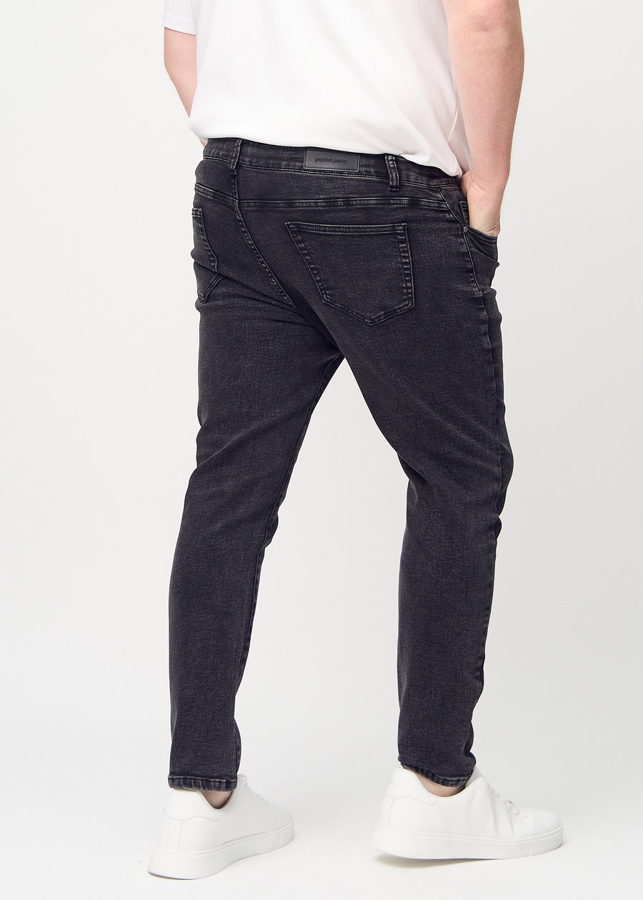 Dark grey denim slim jeans viewed from the back on a plus-size model to show the full product.