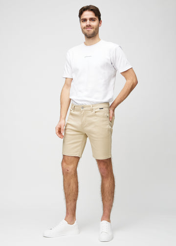Full image of a model in beige middle-slim shorts.