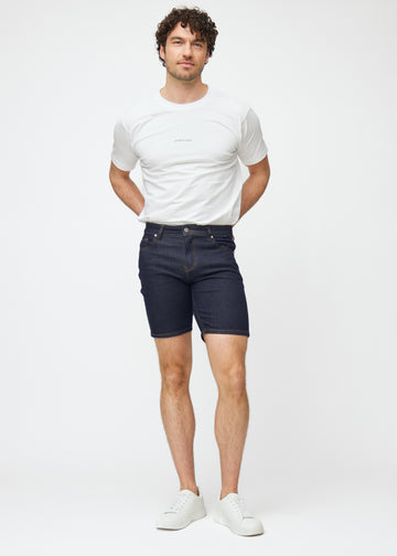 Full image of a model wearing deep dark blue denim shorts for men in the colour Midnights with a slim fit.