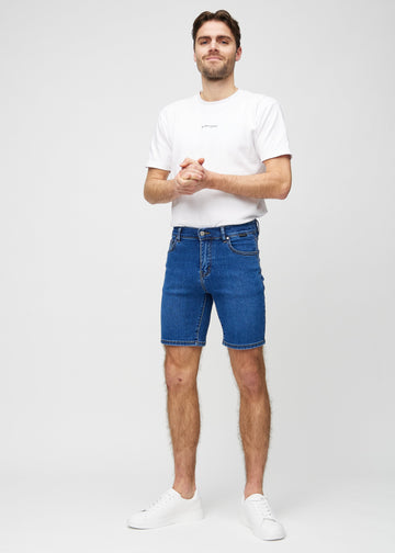 Full image of a model in dark denim middle-slim shorts.