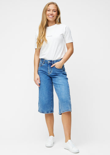 Model viser løse, klassisk blå denim capris i farven Rivers i bevægelse og demonstrerer pasform og materiale.