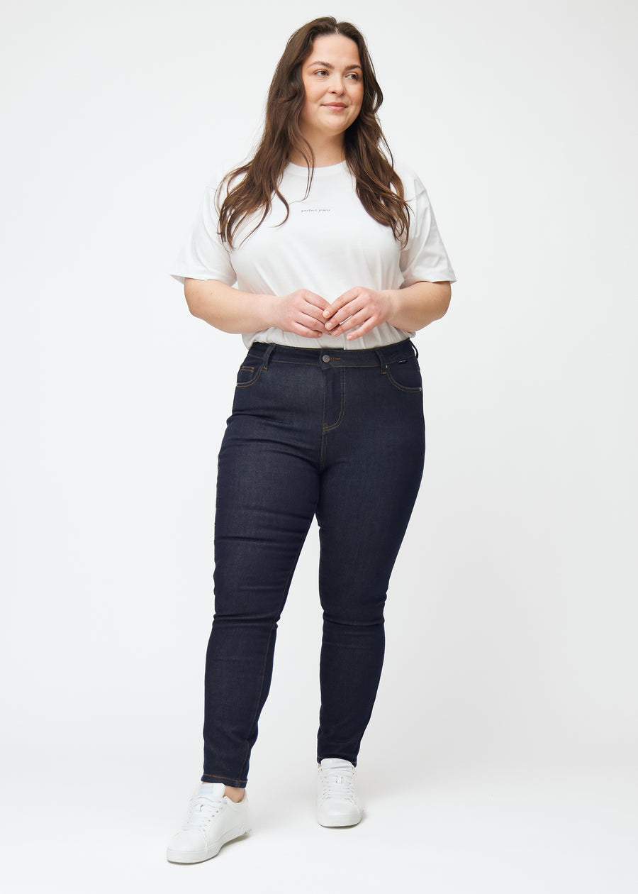 Plus-size model viser dyb mørkeblå denim jeans til kvinder i farven Midnights med skinny pasform i bevægelse.