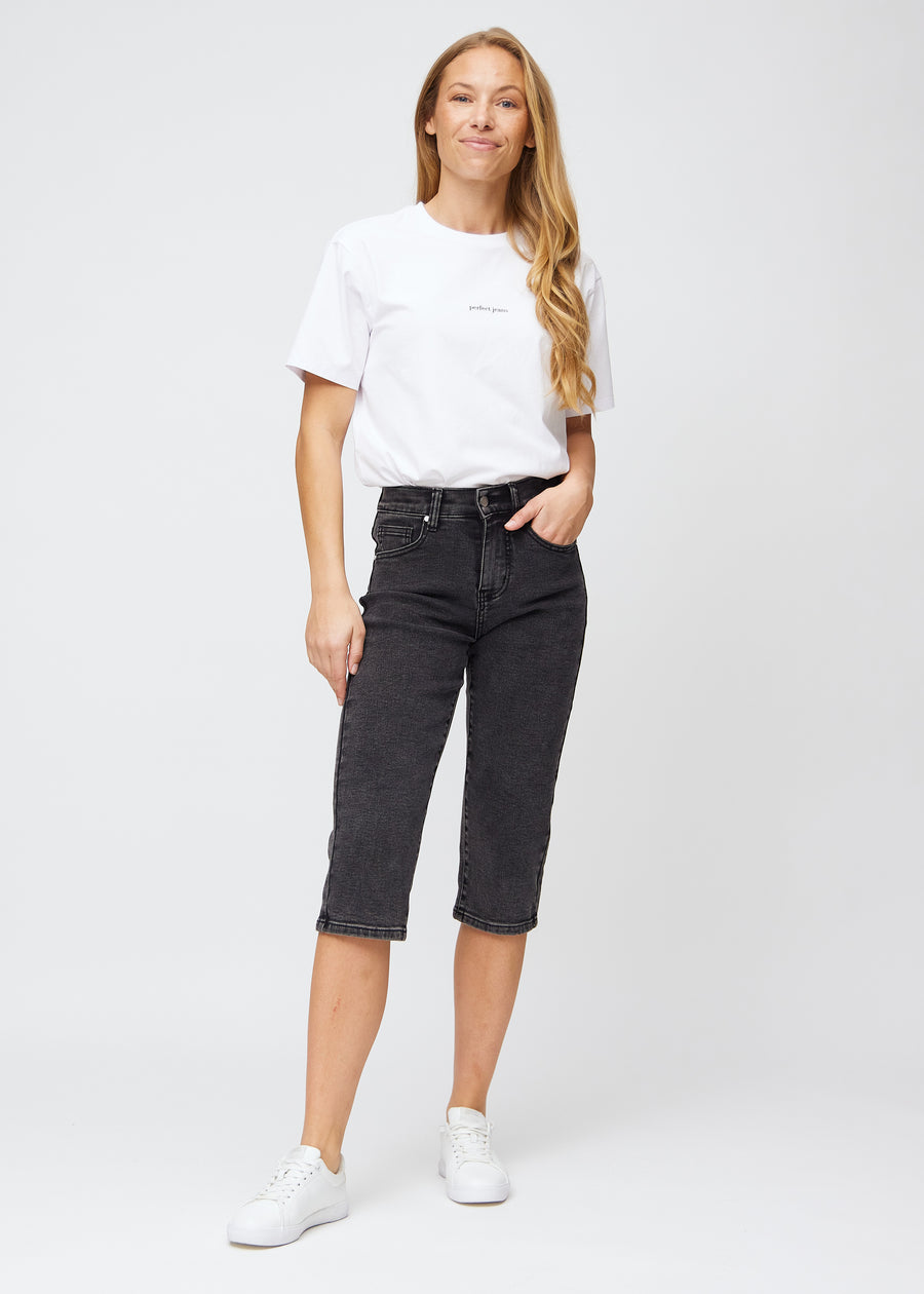 Model går ind i billedet, strækker i sine capris, viser dem frem ved at dreje rundt, og forlader derefter billedet.